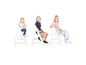 Trois enfants sont assis sur des chaises blanches pour enfants.