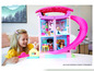 Une maison de poupée Barbie rose avec un toboggan et plusieurs poupées.