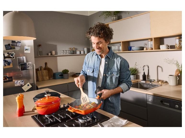 Homme cuisinant dans la cuisine avec une poêle en fonte Silvercrest.