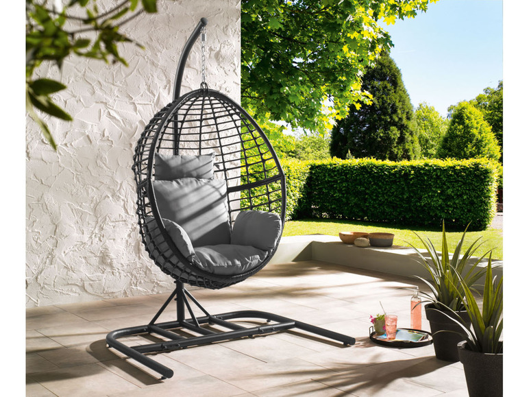 Un fauteuil suspendu noir avec des coussins gris sur une terrasse.