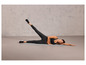Une femme en tenue de sport fait un exercice sur un tapis de yoga.
