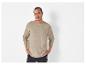 Un homme portant un pull en maille beige à manches longues.