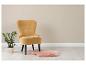 Fauteuil jaune avec une plante et un tapis rose en fausse fourrure sur un parquet clair.