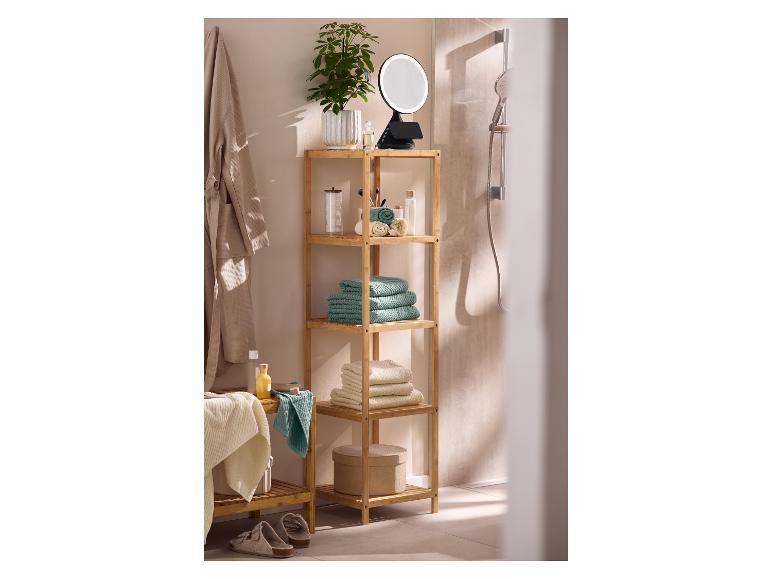Étagère de salle de bain en bambou avec serviettes, cosmétiques et miroir lumineux.
