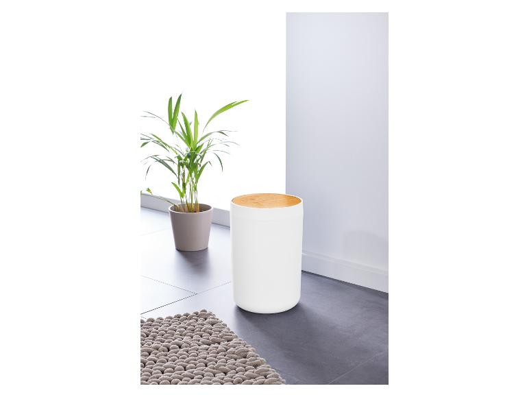 Une poubelle blanche avec un couvercle en bois et un tapis.