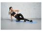 Femme faisant des exercices avec un rouleau en mousse sur un tapis de yoga.
