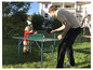Un adulte et un enfant jouent au ping-pong dans le jardin.