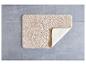 Tapis de bain beige sur un sol en carrelage gris.