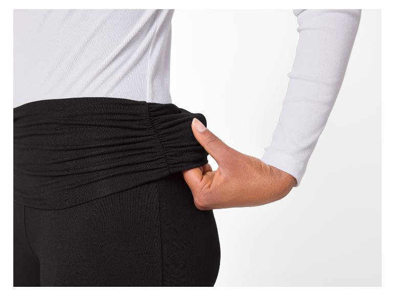 Femme en haut blanc à manches longues et leggings noirs à taille froncée.