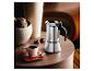 Cafetière moka argentée, tasse de café et chocolats sur une table en bois.
