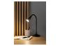 Une lampe de bureau noire, un carnet et des stylos sur un bureau en bois.