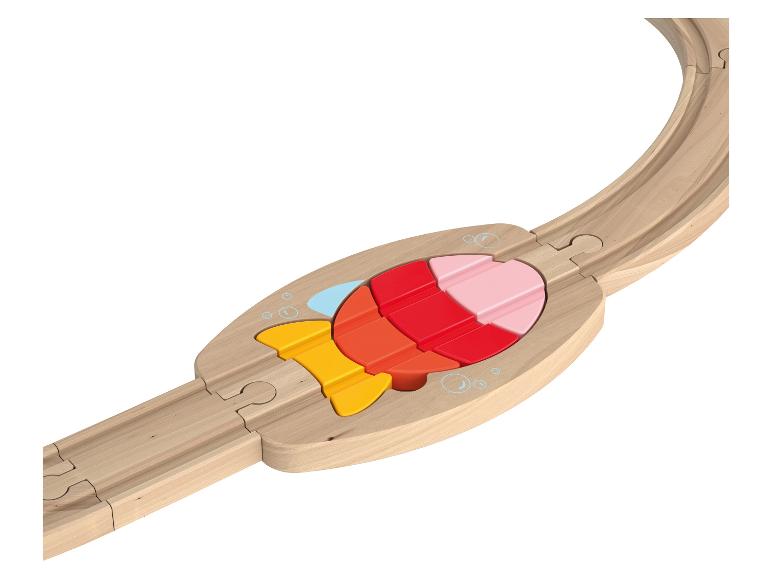 Un rail de train en bois avec un insert de puzzle en forme de poisson coloré.