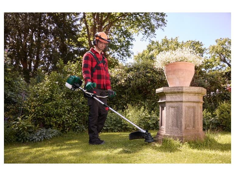 Homme taillant l'herbe autour d'un piédestal en pierre avec la débroussailleuse thermique PARKSIDE PBS 2 F6