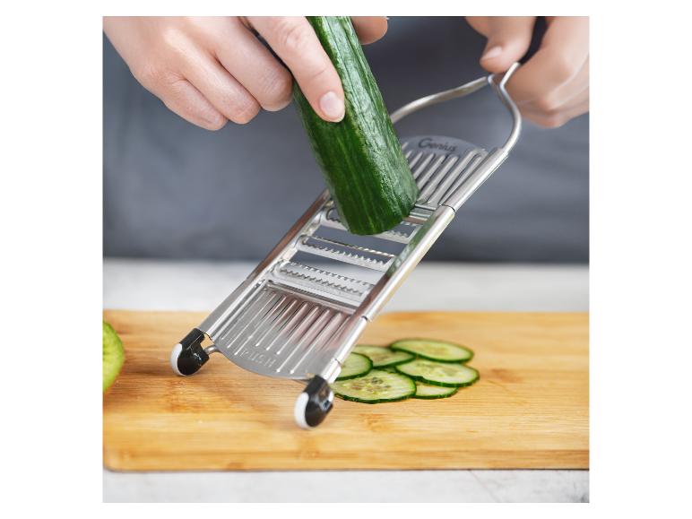 Mains coupant du concombre avec une mandoline Genius sur une planche à découper en bois