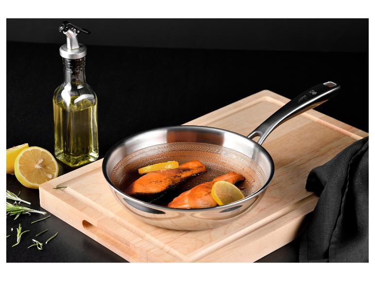 Poêle en acier inoxydable avec saumon et citron sur une planche à découper en bois.