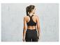 Une femme porte un soutien-gorge de sport noir et un legging.