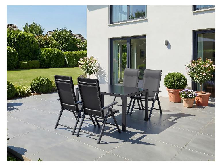 Ensemble de mobilier de jardin avec table et chaises noires sur une terrasse, entouré de verdure.