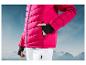 Une veste de ski rose avec un pantalon blanc sur fond de montagnes.