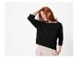 Femme en pull noir avec bordure blanche et pantalon rose.