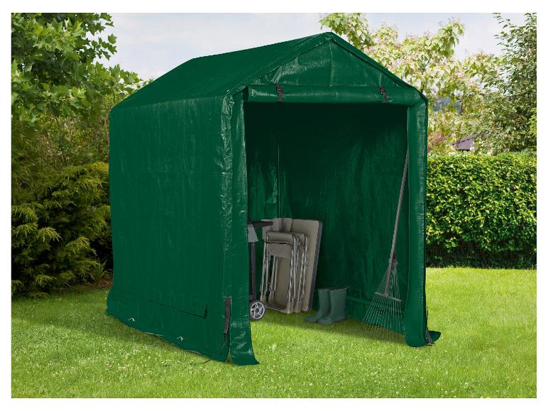 Abri de jardin vert avec outils de jardin et chaises pliantes sur une pelouse.