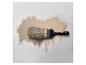 Pinceau avec de la peinture beige sur un mur blanc.