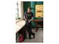 Homme en t-shirt et pantalon noirs tenant une perceuse dans un atelier.
