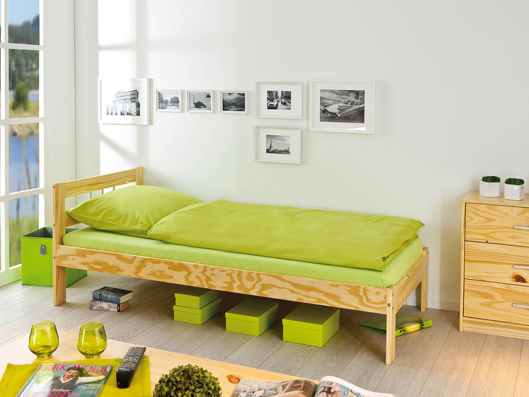 Un cadre de lit en bois avec des draps verts et des boîtes de rangement.