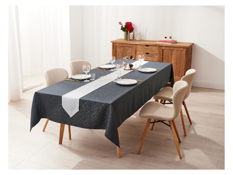 Table à manger avec nappe gris foncé, chemin de table blanc et chaises beiges.