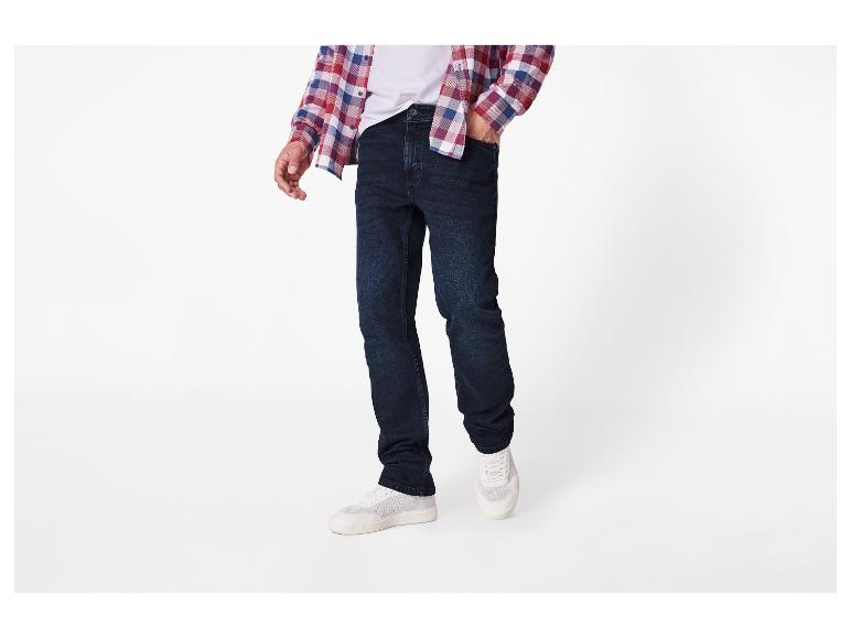 Homme portant un jean bleu foncé, un t-shirt blanc et une chemise à carreaux.