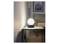 Une lampe de table noire avec un abat-jour rond en verre sur une table basse en bois.