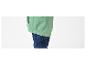 Une veste coupe-vent verte avec un élastique au bas, portée avec un jean.