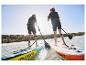 Deux personnes pagaient en paddle sur des planches Crivit.
