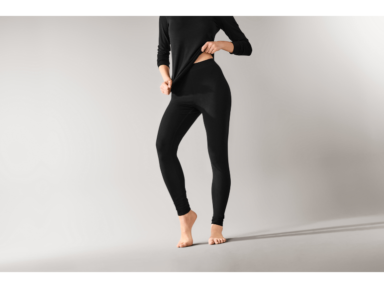 Une femme portant des sous-vêtements thermiques noirs, comprenant un haut à manches longues et un legging