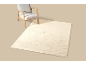 Fauteuil et tapis crème à motif ondulé sur fond beige.