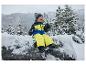 Bébé souriant assis sur un rocher enneigé, portant un pantalon de ski LUPILU®.