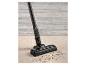 Un aspirateur noir nettoie un tapis.