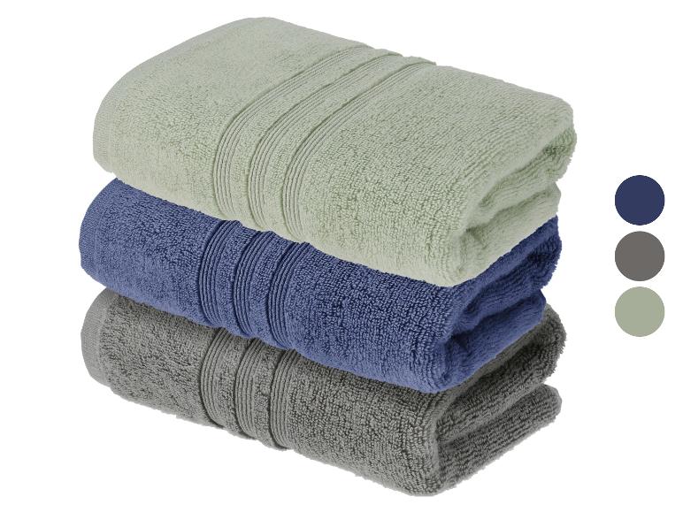 Pile de trois serviettes pliées en vert clair, bleu et gris avec des échantillons de couleur.