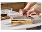 Pierre à aiguiser 2-en-1 SILVERCREST® utilisée pour affûter un couteau de cuisine sur un socle en bois