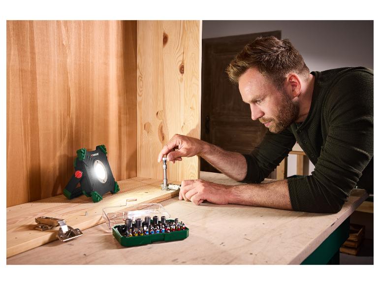 Un homme utilise le projecteur de chantier sans fil PARKSIDE PAAL 6000 E1 pour monter un meuble.