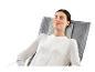 Une femme se détend dans un fauteuil gris avec un coussin.