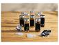 Ensemble de bocaux à épices en verre avec couvercles métalliques, entonnoir et étiquettes noires sur une table en bois.