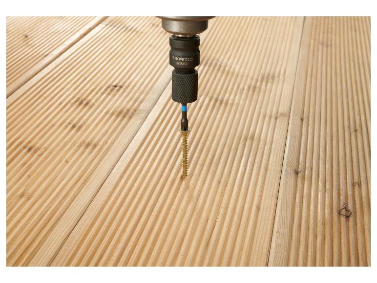 Visser une vis dans une planche de terrasse en bois avec une visseuse sans fil.