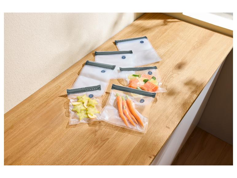 Sacs sous vide avec carambole, carottes et saumon sur un comptoir en bois.