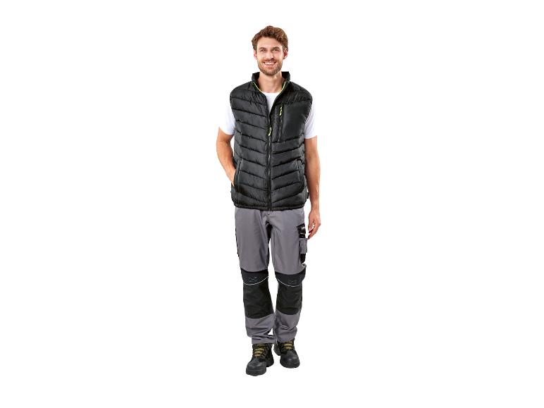 Un homme portant une veste noire et un pantalon de travail gris.