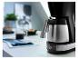 Cafetière avec verseuse isotherme et écran numérique sur une table avec café et collations.