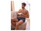 Un homme en boxer avec un motif de cœurs mange un croissant.