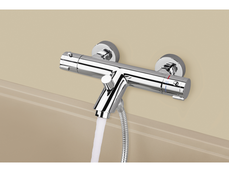 Mitigeur thermostatique chromé pour douche de baignoire avec eau coulant dans la baignoire.