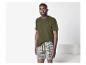 Homme en t-shirt vert olive et caleçon rayé, debout dans une pièce.