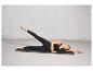 Une femme en tenue de sport fait des exercices sur un tapis de yoga noir.