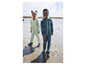 Deux enfants en salopettes vertes sur la plage.
